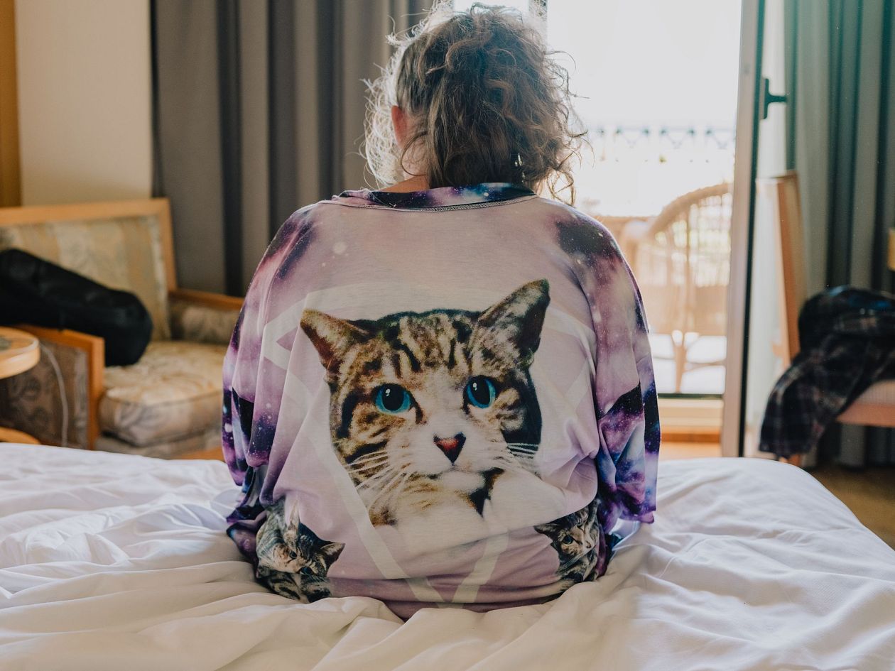 A girl in a pyjama with a cat on the bed.