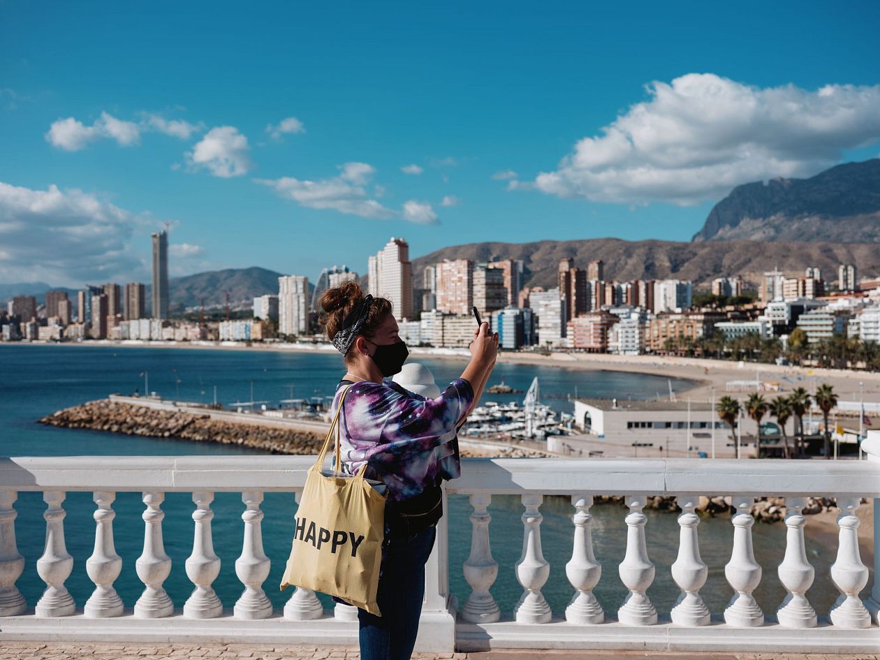 Young woman tourist with a bag on the background of the city Benidorm