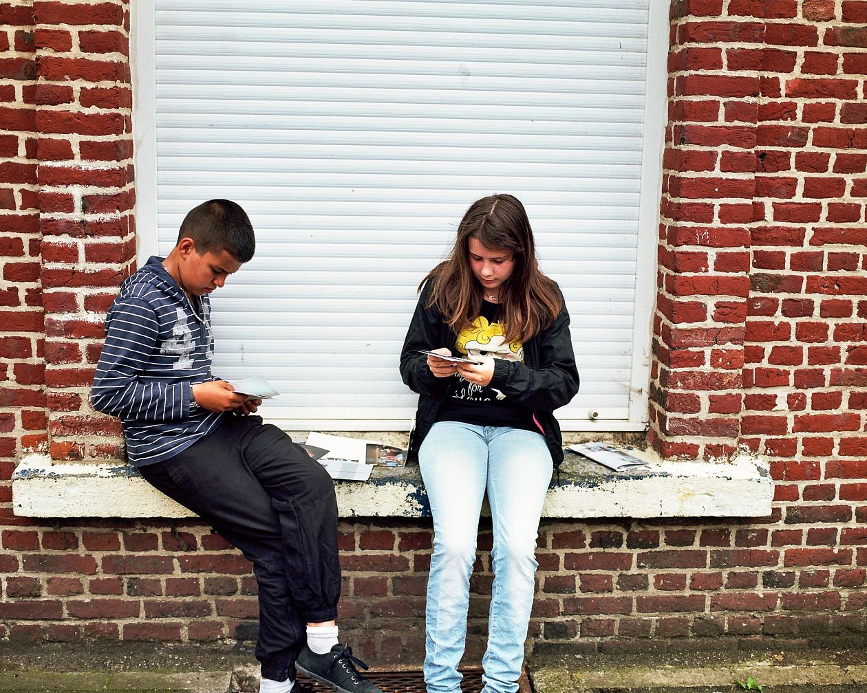 Young couple sitting on a wall with a cup of coffee in their hands. Lille, France