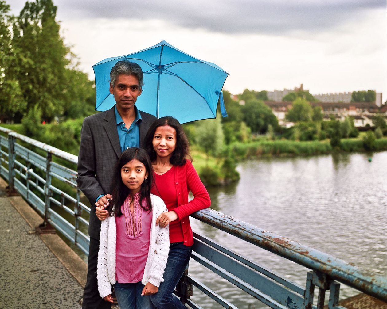 Indian family with umbrella standing on bridge in the park. Lille, France