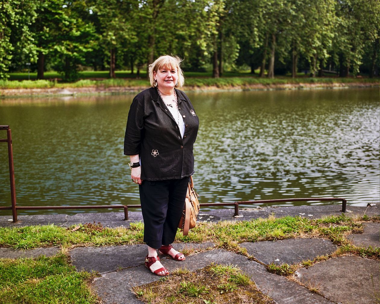 Portrait of a happy senior woman standing by the river in park
