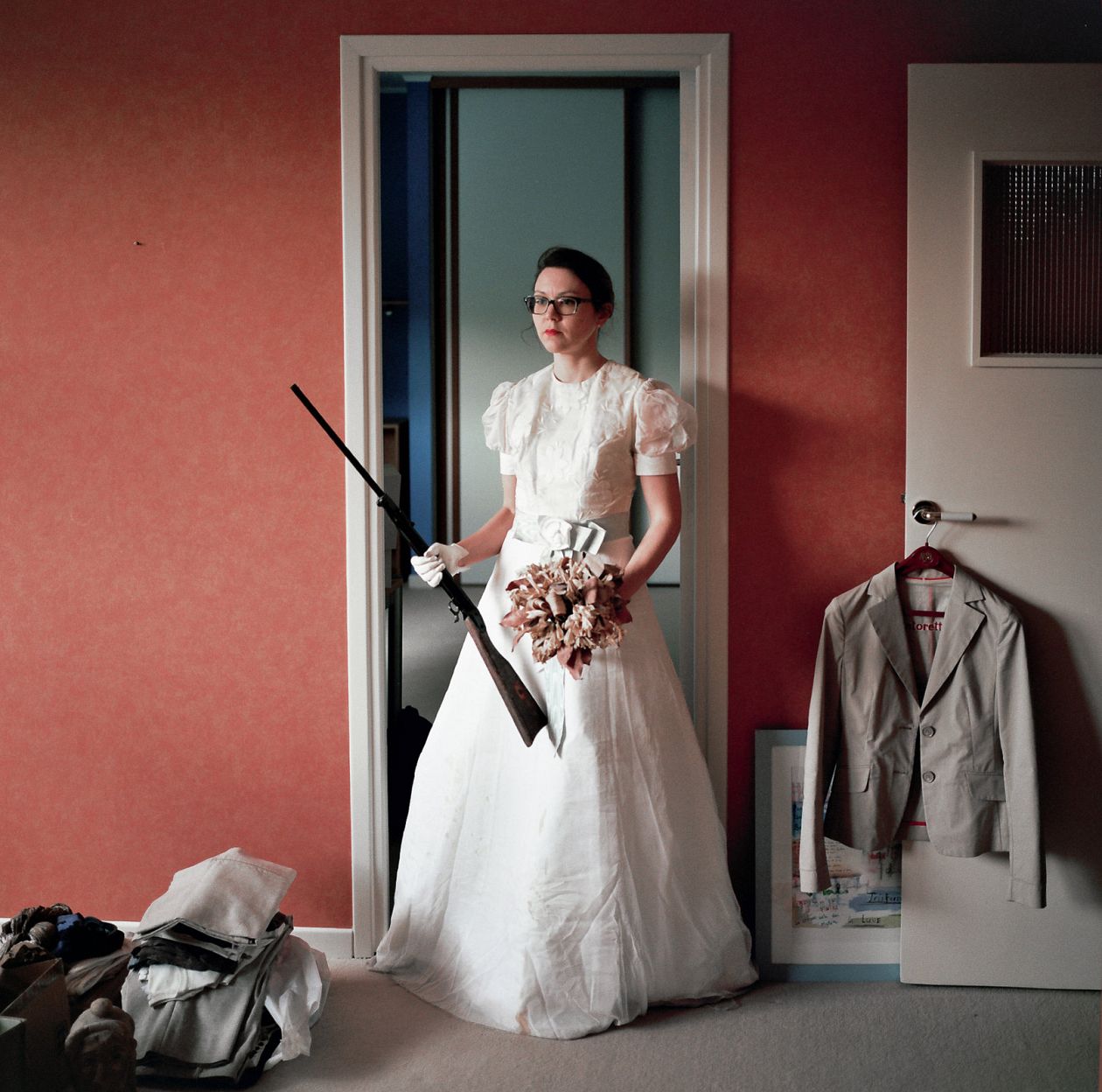 bride with a gun on the background of a red wall.