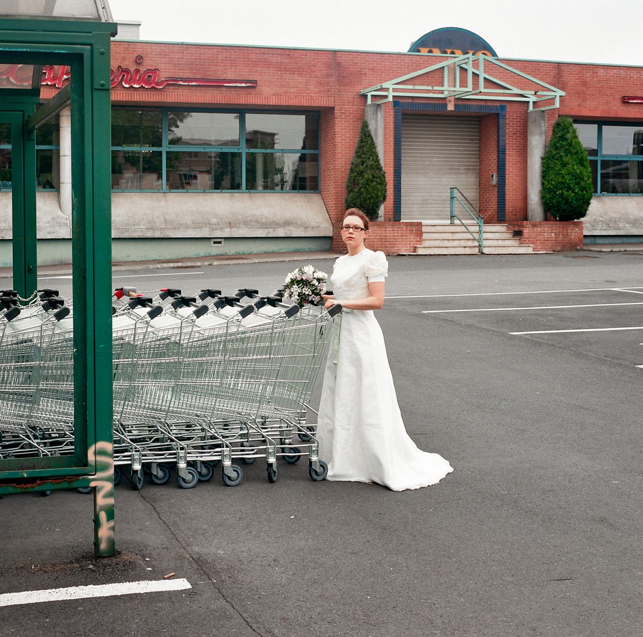 Beautiful bride in a white wedding dress with a bouquet of flowers in a shopping cart