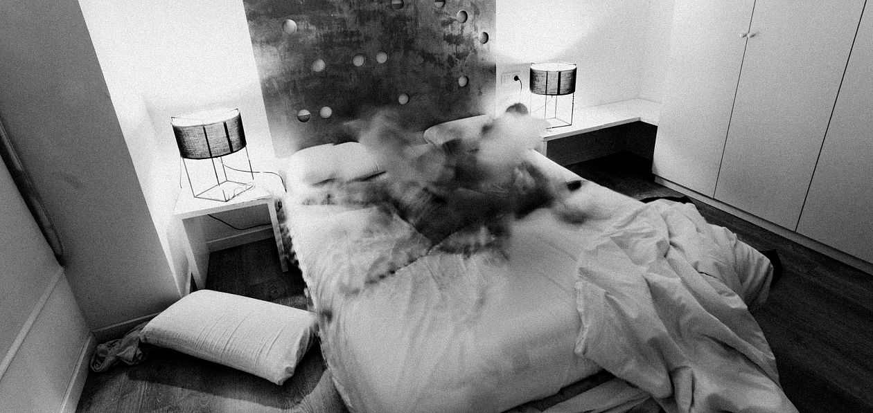A black and white image of a messy bed in a hotel room