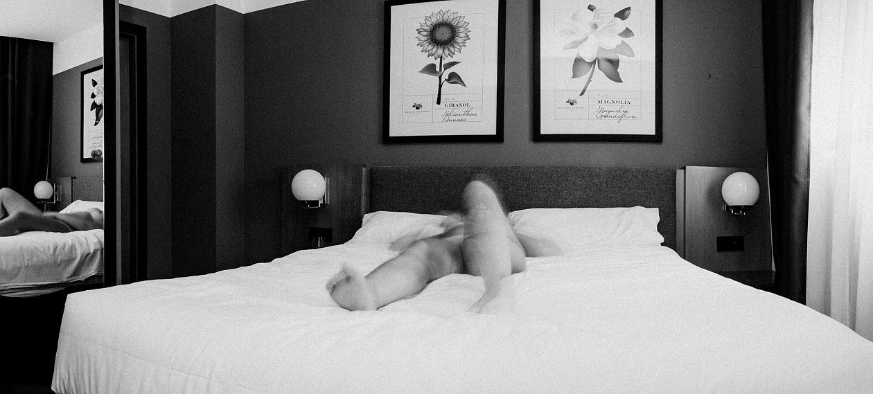 Young woman lying on the bed in hotel room, black and white