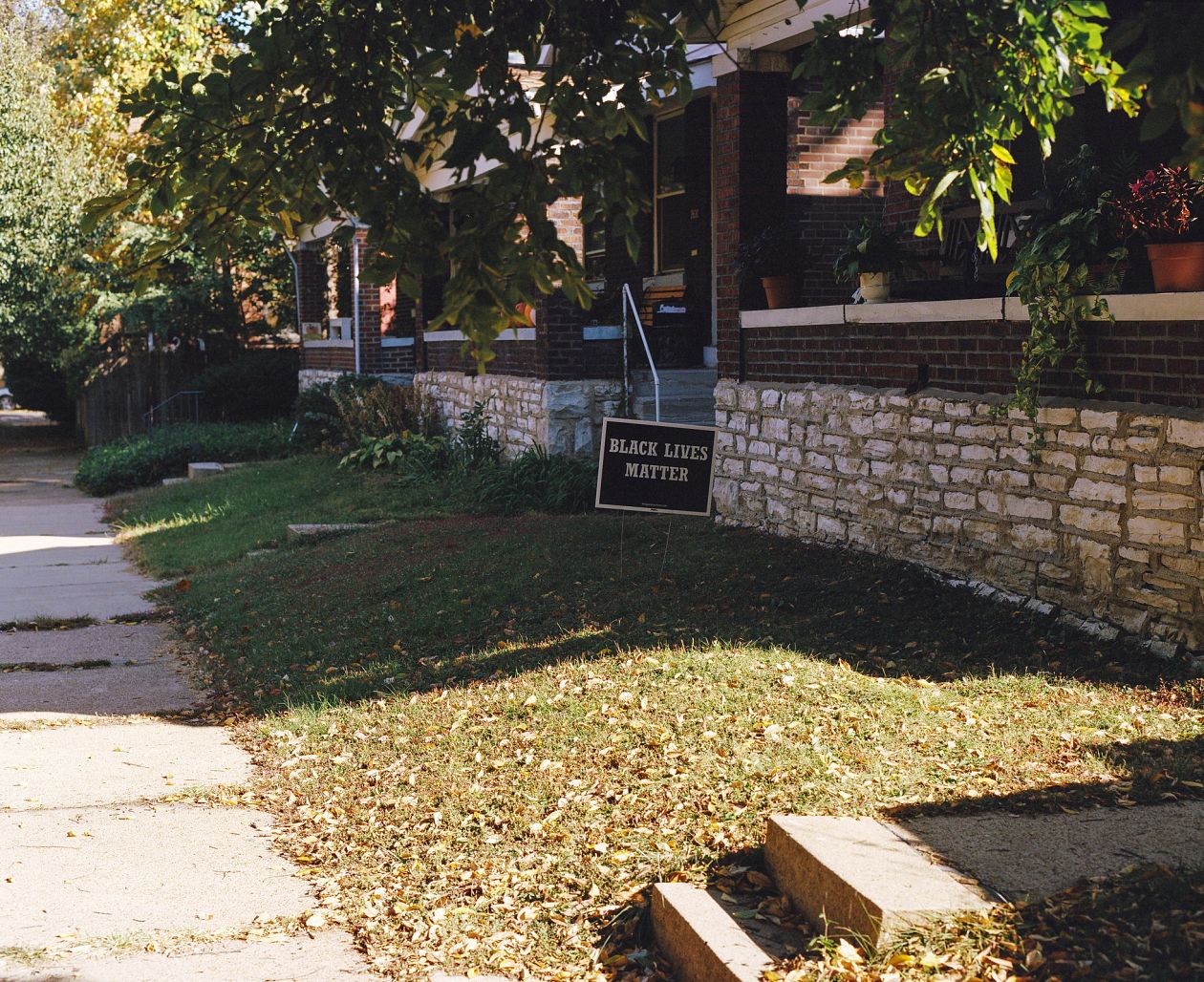 Autumn leaves in front of a house building with a black lives matter sign.