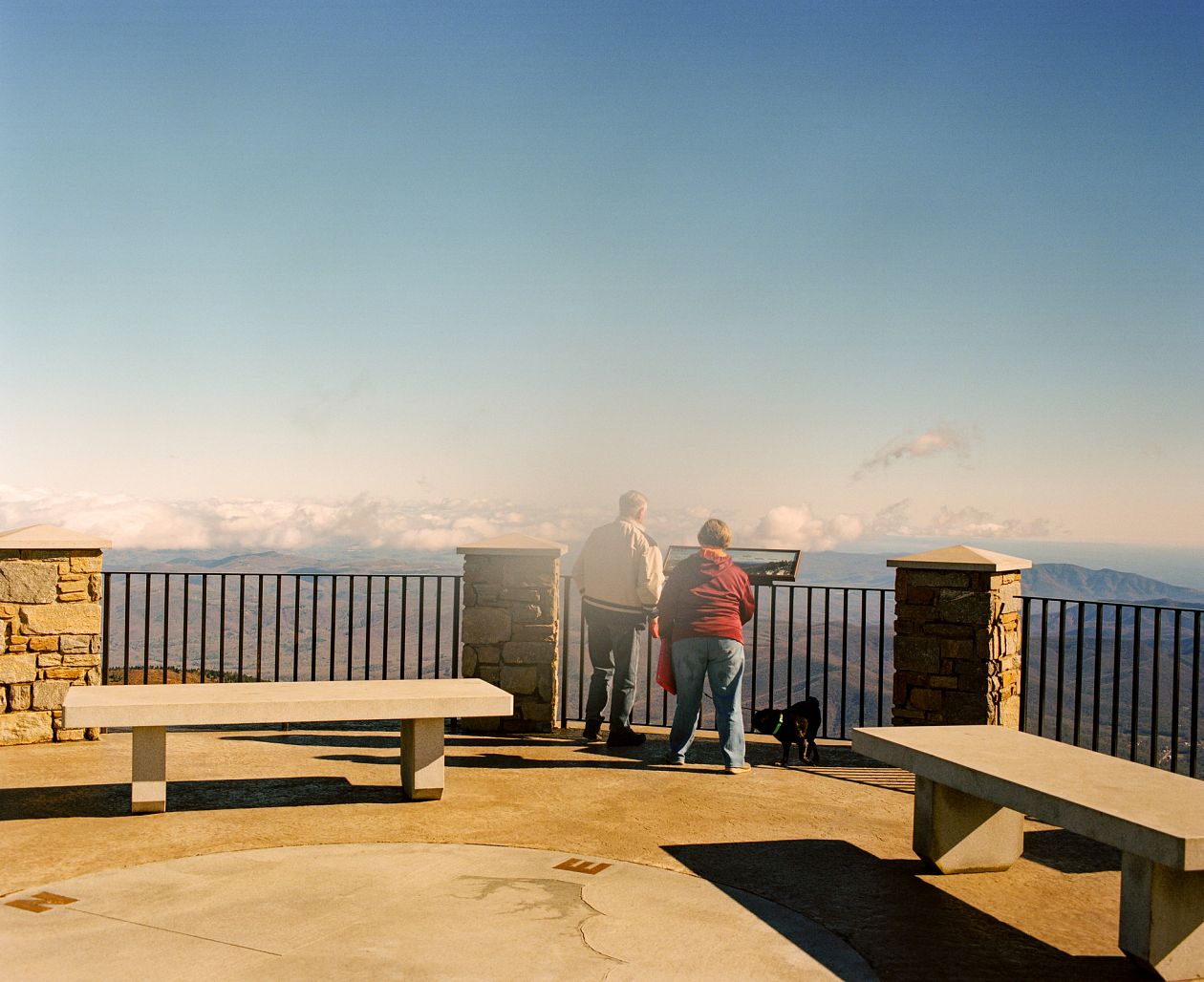 Tourist couple looking at the view from the observation deck on the mountain
