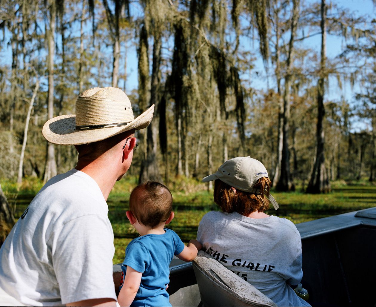 Father and his two kids sitting on a boat and looking at the lake in Louisiana